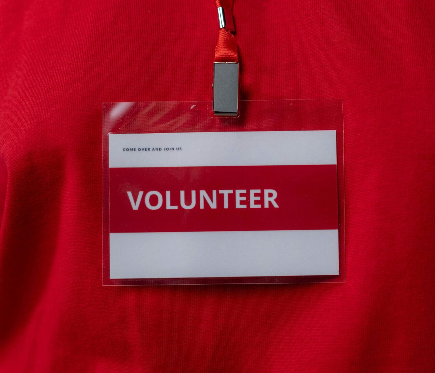 A close-up of a volunteer name tag hanging on a red lanyard, symbolizing community service.